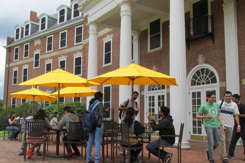 Students studying, talking and dining at the tables on the Graduate Life Center patio
